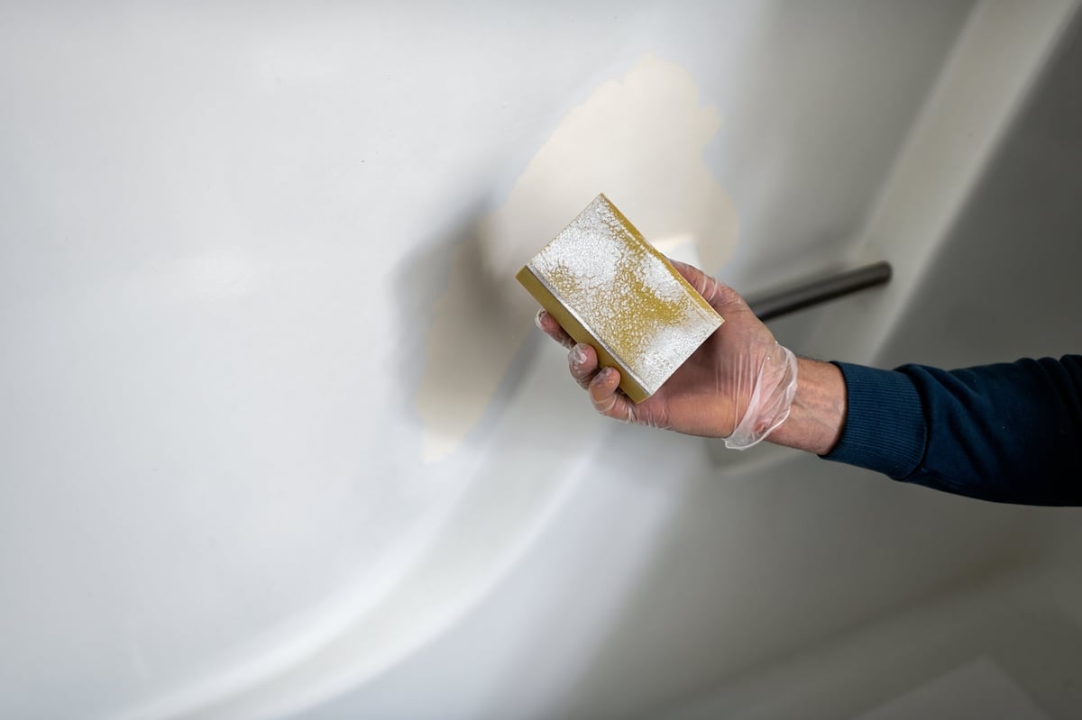 Technician refinishing a bathroom tub wall